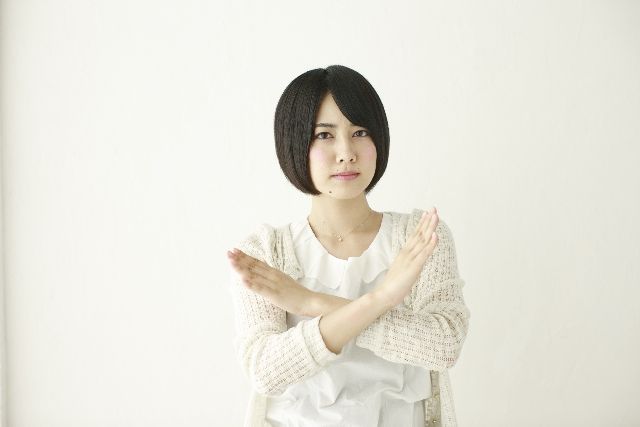手でバツを作る女性